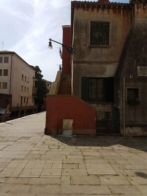 A building with a red facade, a visible staircase, and a small door. - Grimaldi Apartments - Petit Maison (Venice)
