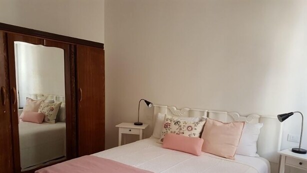 Ein Schlafzimmer mit Bett, Nachttischen, einem Spiegel und einem Kleiderschrank.