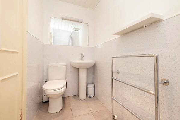 Un baño pequeño y limpio con inodoro, lavabo y ducha.
