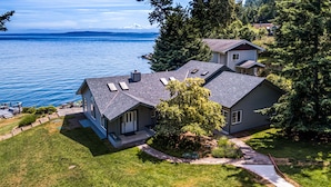 A two-story house with a sloped roof, a small detached garage, and a well-maintained lawn. - Orcas Island, Mt. Baker Beach House, #289 (Eastsound)