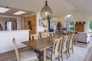 Une cuisine spacieuse avec un coin repas, des meubles en bois, une grande table et un lustre.