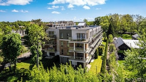 Un edificio de varios pisos con balcones, rodeado de abundante vegetación y árboles.
