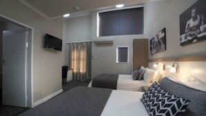 A hotel room with two beds, a TV, a window with curtains, and a mounted artwork.