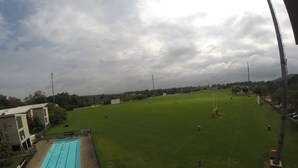 A large indoor sports facility with a swimming pool, a green field, and a covered seating area.