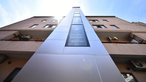A tall building with a central glass elevator shaft and multiple windows on each floor. - Hotel Paliashvili (Batumi)
