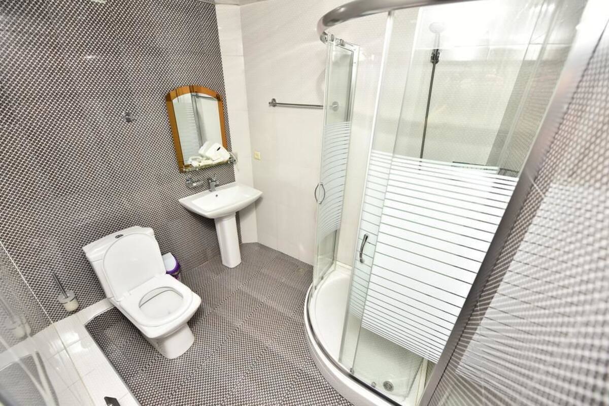 A modern bathroom with a toilet, sink, and glass-enclosed shower.