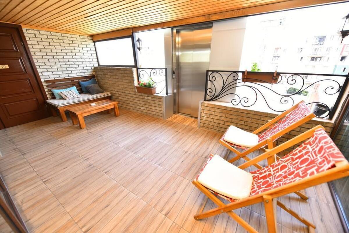 A balcony with a wooden floor, a bench, and two lounge chairs.