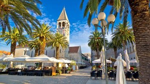 A cobblestone square with outdoor seating, palm trees, and a historic building with a bell tower. - Apartment in Sevid with Seaview, Terrace, Air condition, WIFI (4746-3) (Sevid)