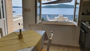 A balcony with a table set for two, overlooking a body of water and a distant island. - Apartment in Sevid with Seaview, Terrace, Air condition, WIFI (4746-3) (Sevid)