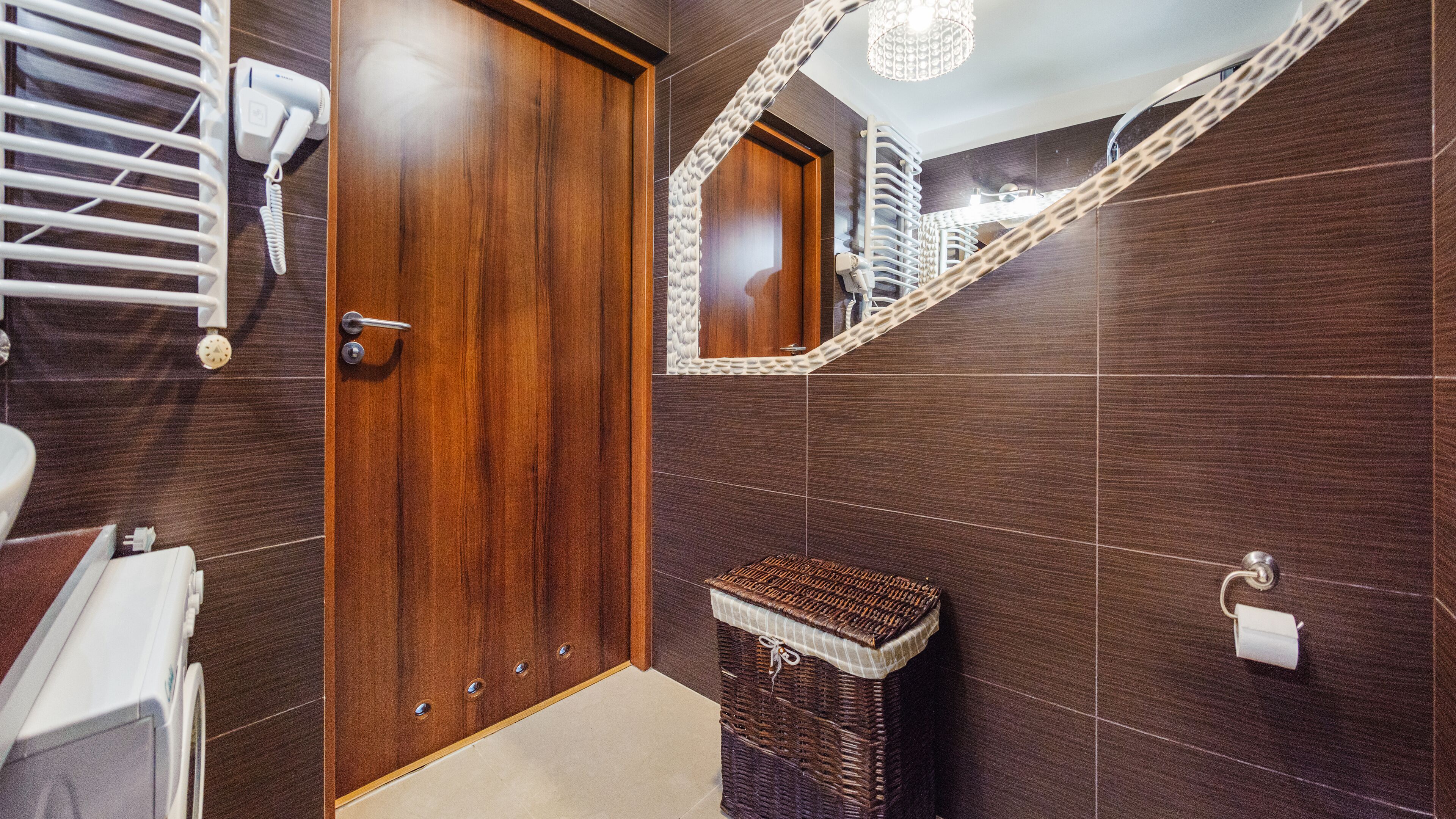 Une salle de bain moderne avec une porte en bois, un miroir, un panier en osier et un porte-serviettes.