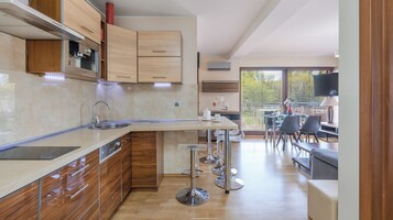 Cozinha moderna com forno embutido, pia e área de jantar com mesa e cadeiras.