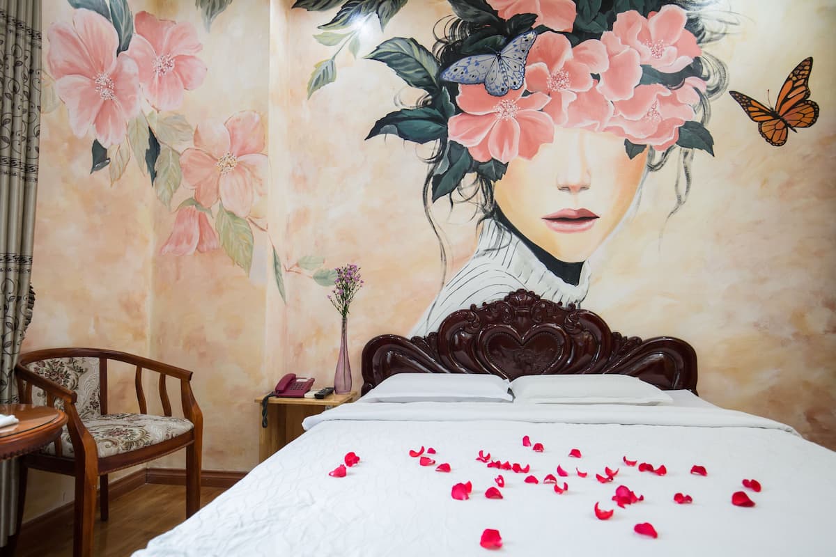 Une chambre à coucher comprenant un lit, une chaise et un mur décoré de motifs floraux et de papillons.