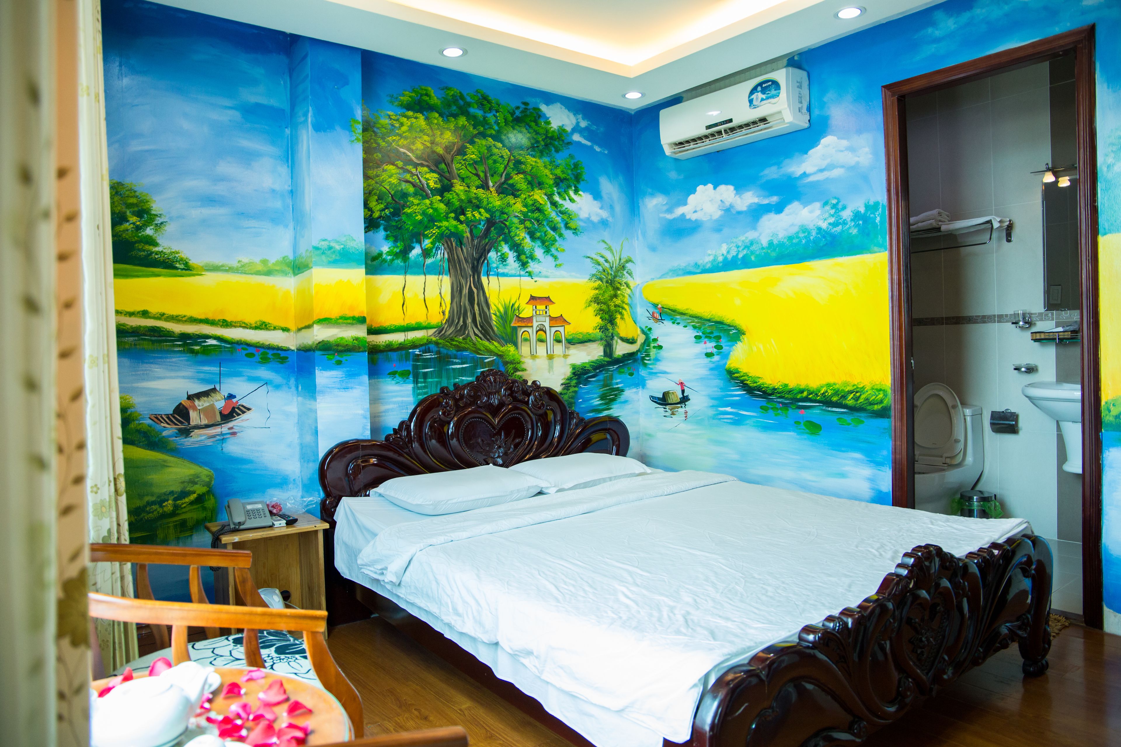 Een slaapkamer met een groot bed, een houten nachtkastje, een stoel en een muurschildering van een landschap.