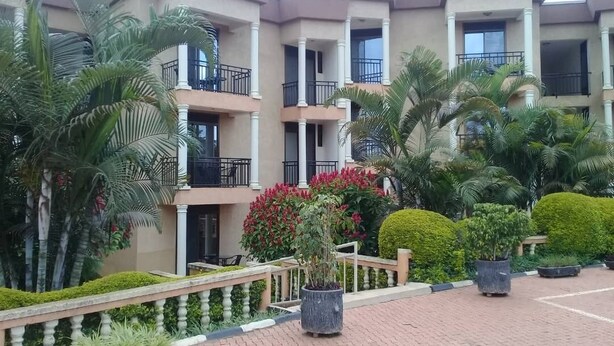 A multi-story building with balconies, surrounded by well-maintained gardens and palm trees. - Kami Executive Apartments (Kigali)