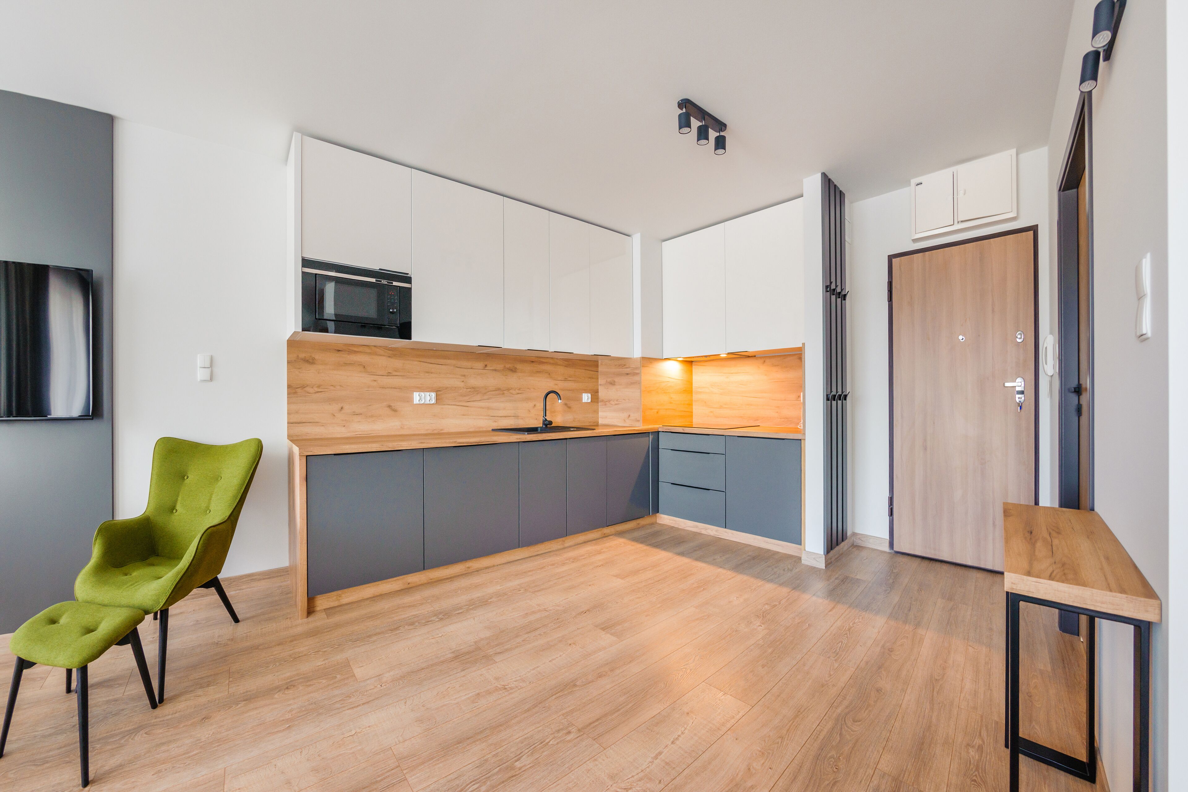 A modern kitchen with a wooden countertop, a green chair, and a small table.