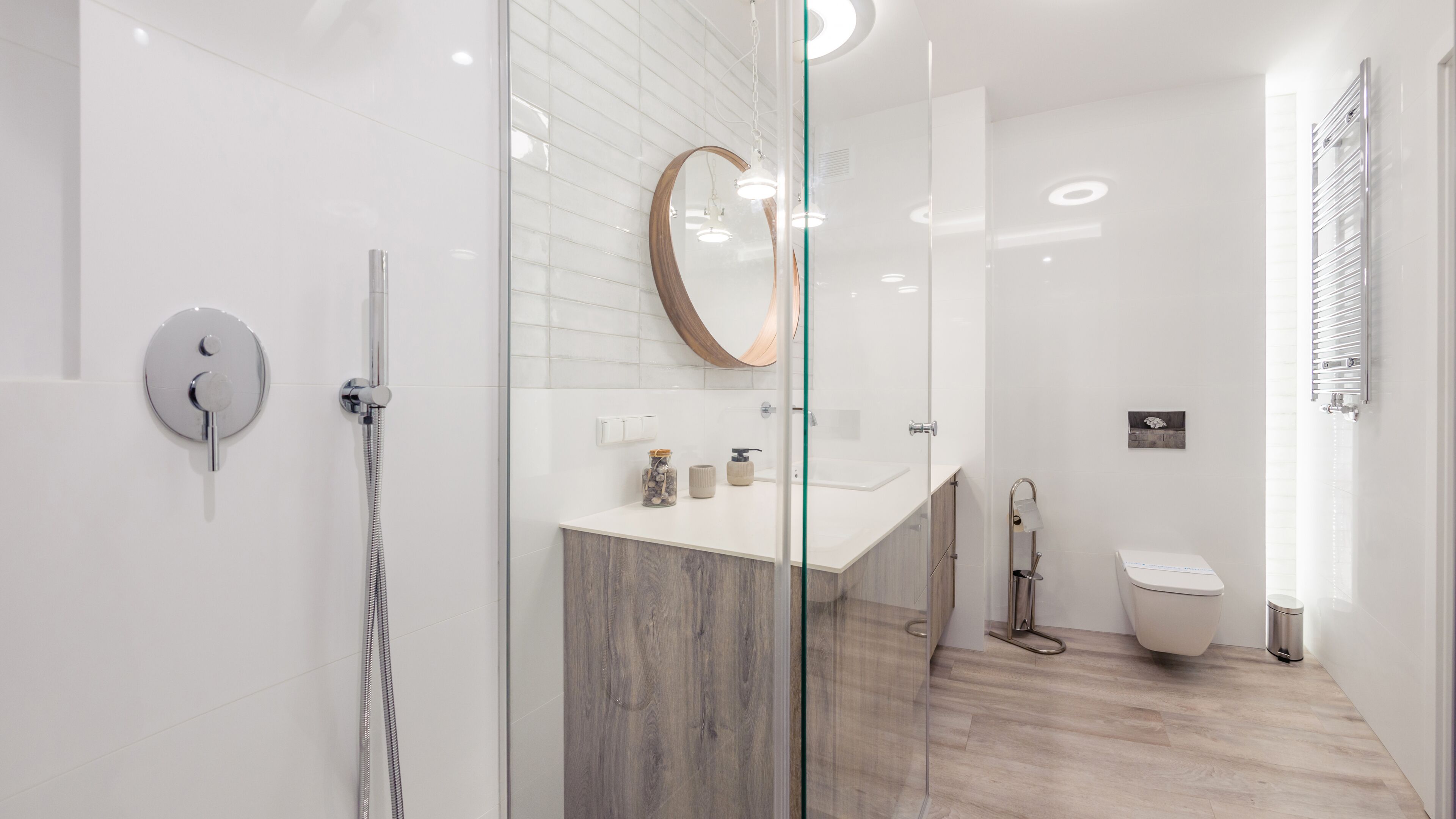 A modern bathroom with a glass shower enclosure, a wooden vanity, and a toilet.