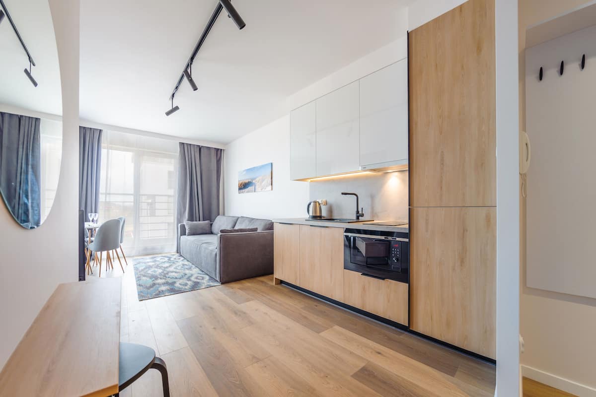 A modern kitchen with wooden cabinets, a built-in oven, and a dining area with a table and chairs.