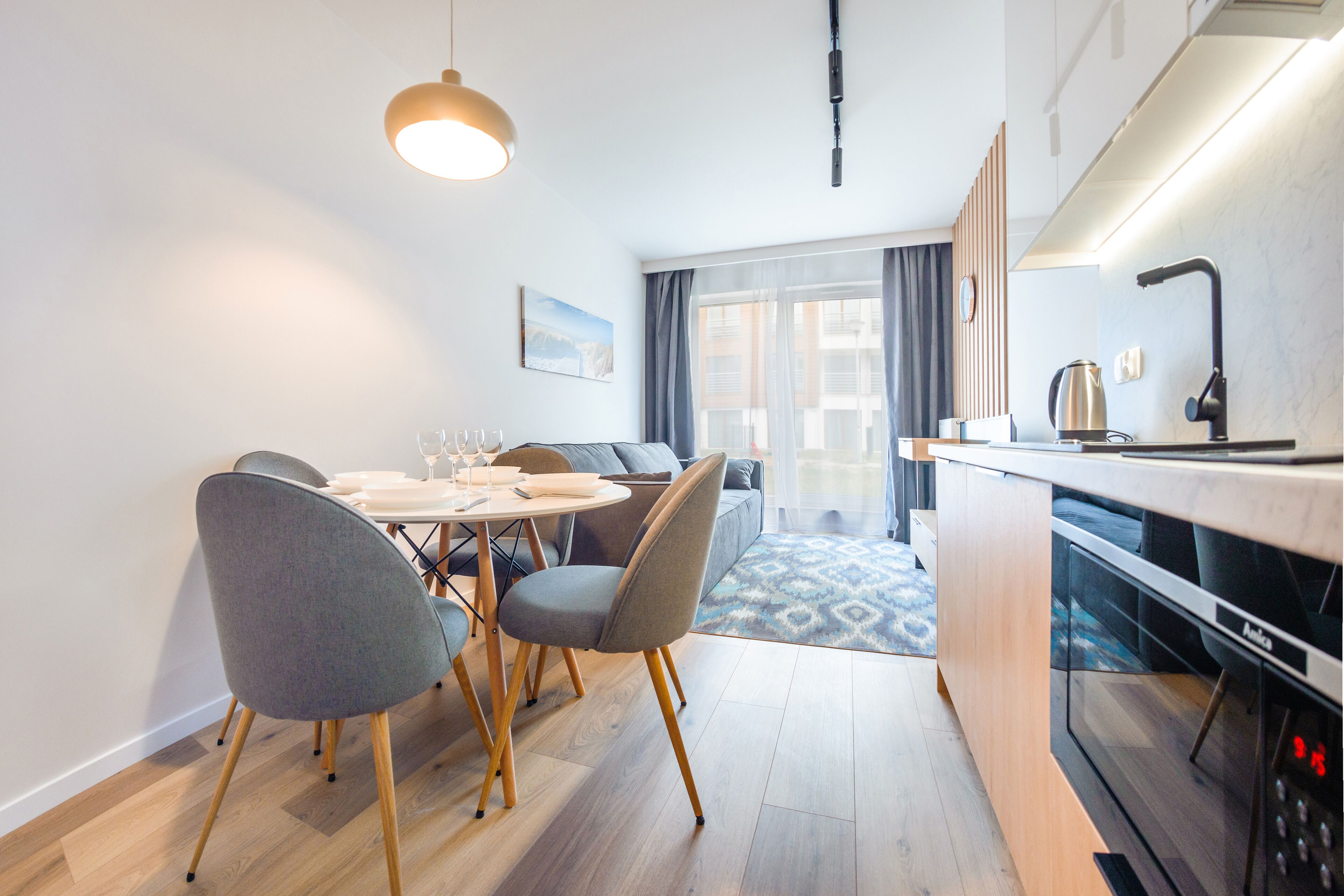 Una cocina moderna con microondas, hervidor y comedor con mesa y sillas.