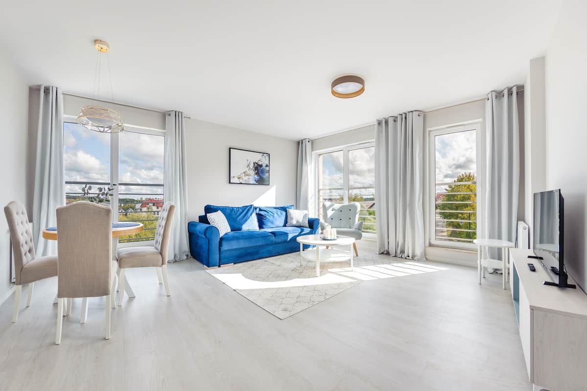 A modern living room with a blue sofa, white coffee table, and a TV on a wooden stand.