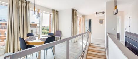 Un apartamento moderno con comedor, una escalera y vistas de la ciudad.