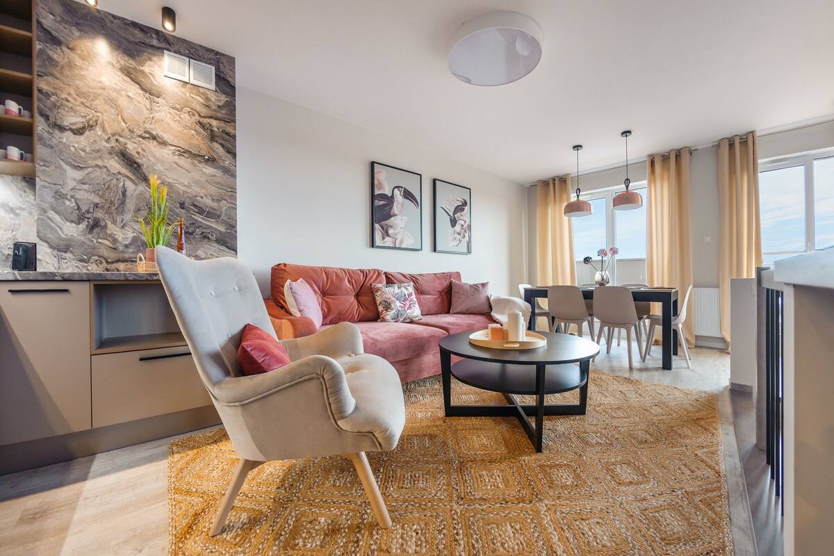 A modern living room with a sofa, armchair, coffee table, and dining area.
