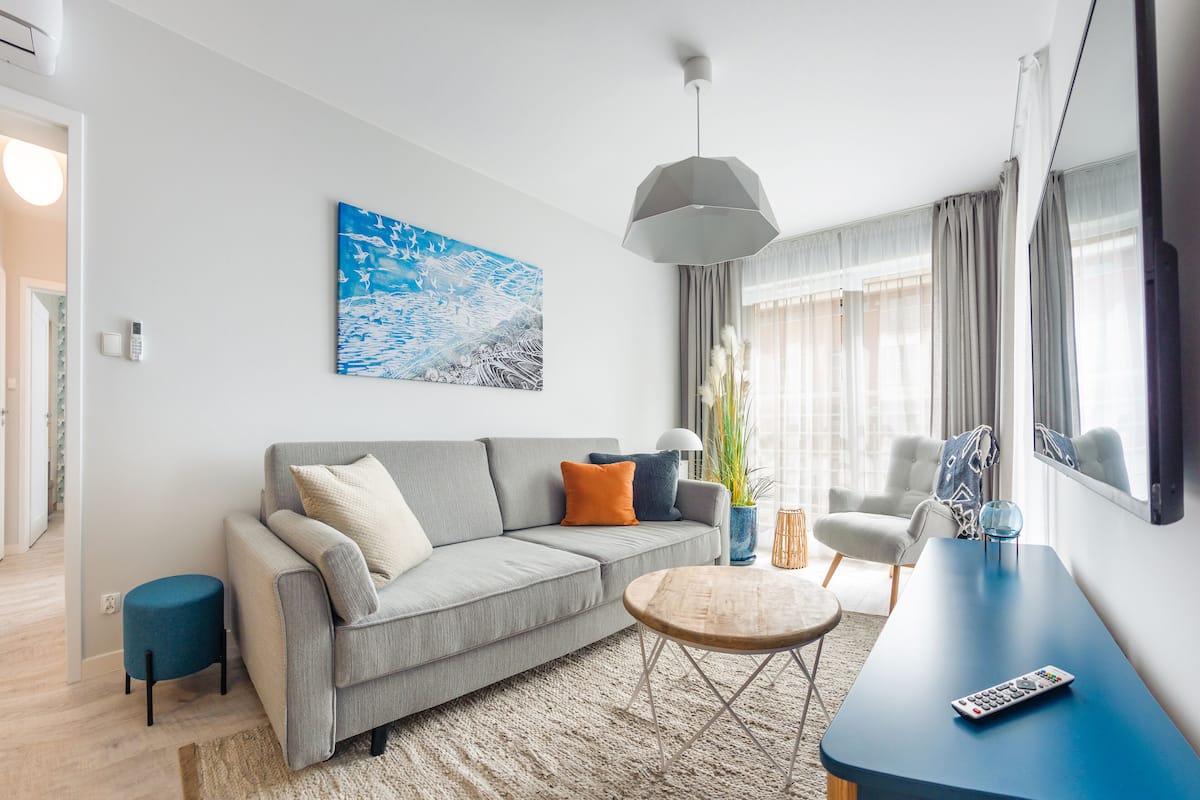 A modern living room with a grey sofa, a round coffee table, and a blue side table.