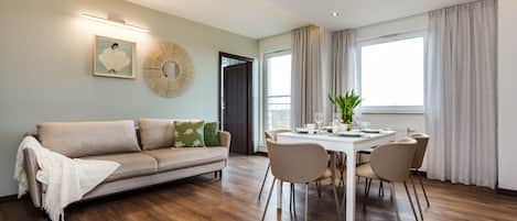 A modern living room with a sofa, dining table, and chairs.