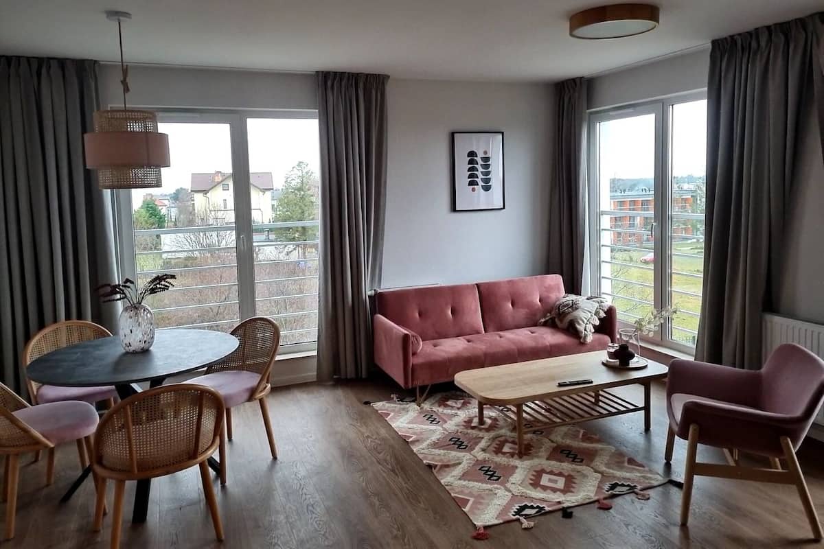 A modern living room with a sofa, coffee table, and dining set.