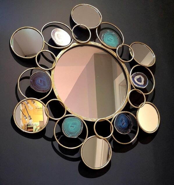 A wall-mounted mirror with a central reflective surface surrounded by multiple smaller mirrors.
