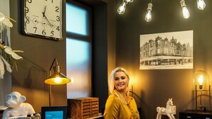 A hotel reception desk with a clock, a vintage light fixture, a framed cityscape photo, and a statue of a horse. - Mode Hotel Lytham (Lytham St. Anne's)