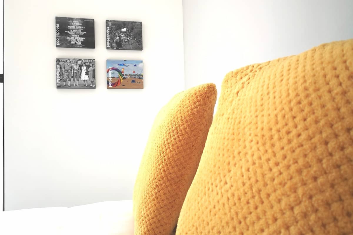A bedroom with a bed, white bedding, and four framed pictures on the wall.