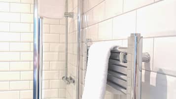 Un bagno moderno con box doccia in vetro, pareti piastrellate di bianco e un porta asciugamani.