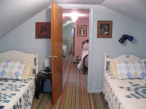 Cozy room with two single beds, a table, and artwork on the walls.