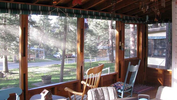 A cozy cabin with large windows, wooden furniture, and a view of a forested area.