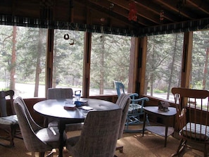 Enjoy meals in a serene forest setting with a round table and comfortable seating for four.