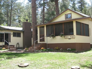 Welcome to BIG PINE, a charming single-story home surrounded by a lush lawn and beautiful flower beds.