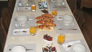 Un bufé de desayuno con croissants, fruta y zumo de naranja.