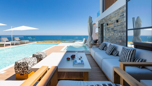 A modern outdoor lounge area with a pool, seating, and a view of the ocean. - Wave Villa, Seaside Living &  Your Own Beach Spot (Panormos in Rethymno)