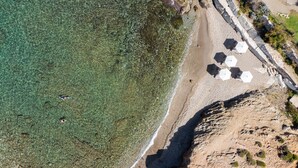 An aerial view of a beach with clear water, a rocky shoreline, and umbrellas. - Wave Villa, Seaside Living &  Your Own Beach Spot (Panormos in Rethymno)