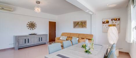 Een moderne woonkamer met een zithoek, een eettafel en een grote klok aan de muur.
