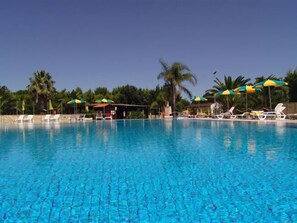 Una piscina al aire libre de temporada, sillones reclinables de piscina