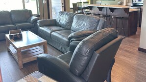 Ein modernes Wohnzimmer mit einer Ledersofa, einem Holztisch und einem Essbereich mit einer Bar.