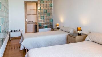 Ein Hotelzimmer mit zwei Betten, einem kleinen Tisch und einem Nachttisch mit Lampen.