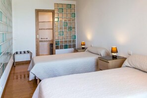 Una habitación de hotel con dos camas, una mesita pequeña y una mesita de noche con lámparas.