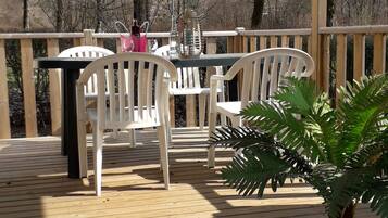 A wooden deck with a table and chairs, surrounded by a wooden railing, and a potted plant.