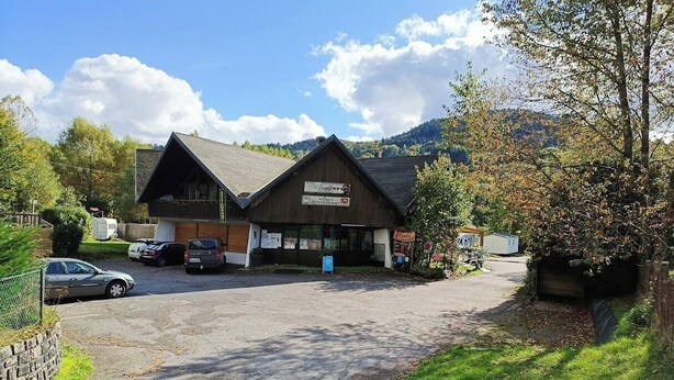 Een gebouw met een bord waarop een restaurant staat aangegeven en een parkeerplaats met auto's.