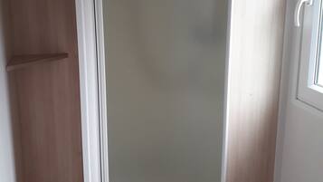 A room with a sliding door, a wooden wardrobe, and a small window.