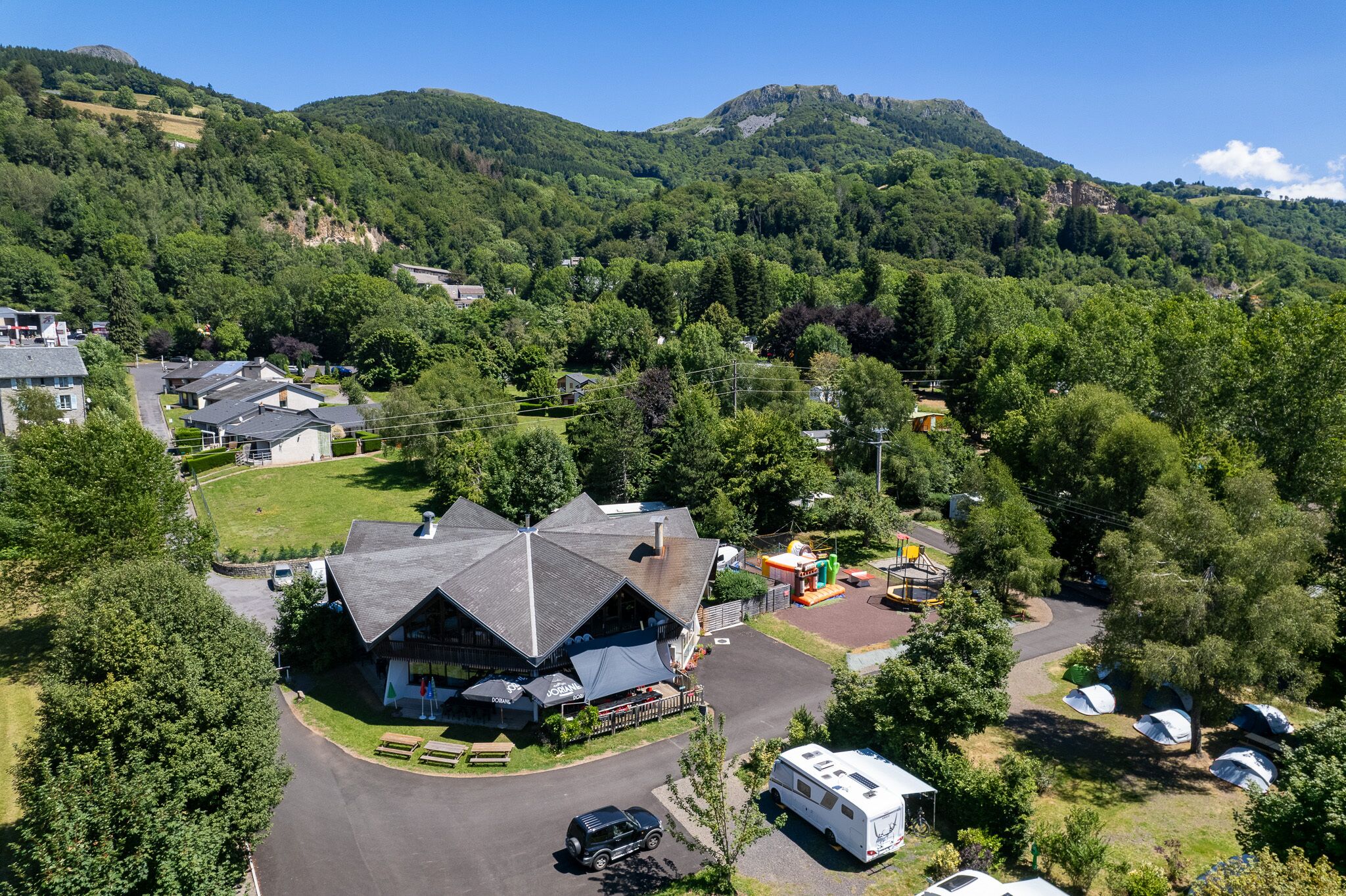Un chalet avec une vue impressionnante sur les montagnes, un espace de stationnement et plusieurs tentes.
