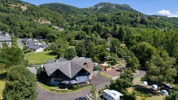 Un chalet avec une vue impressionnante sur les montagnes, un espace de stationnement et plusieurs tentes.