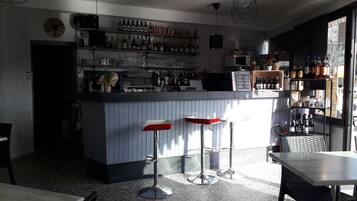 A bar area with a counter, stools, and a variety of bottles and glasses.